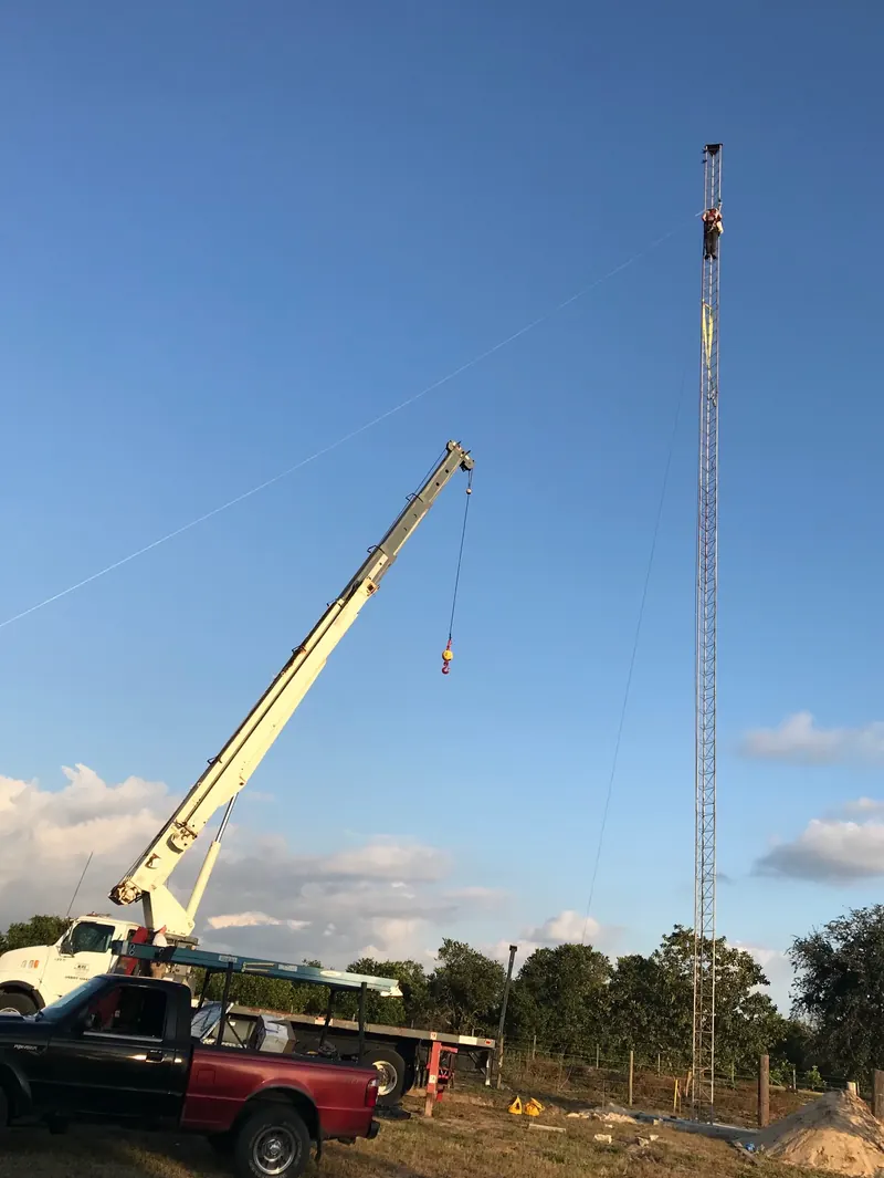 A crane truck raising a tall tower mast