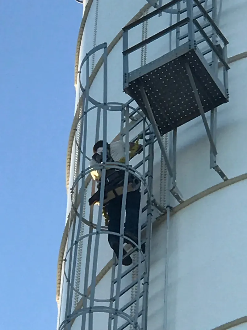 A technician climbing the ladder of a water tower